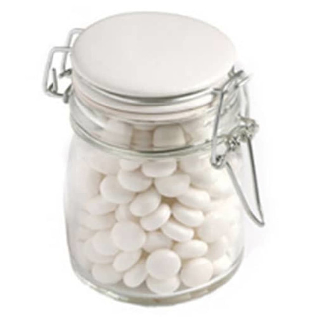 A glass clip lock jar filled with white mints, featuring a metal clasp and a white lid.