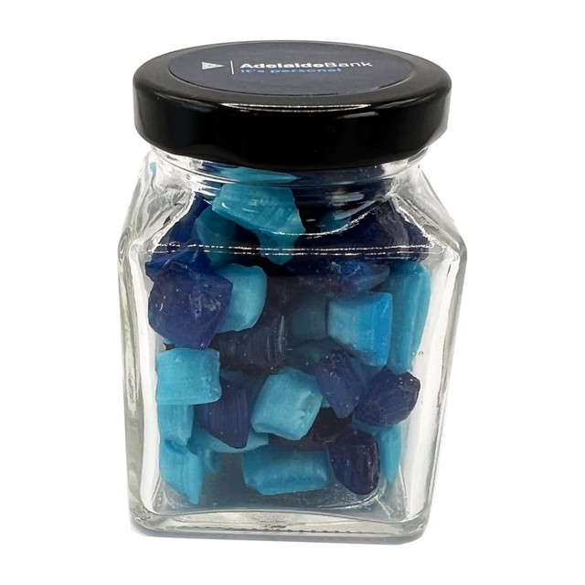 A small glass jar filled with blue and dark blue humbugs, topped with a black lid.