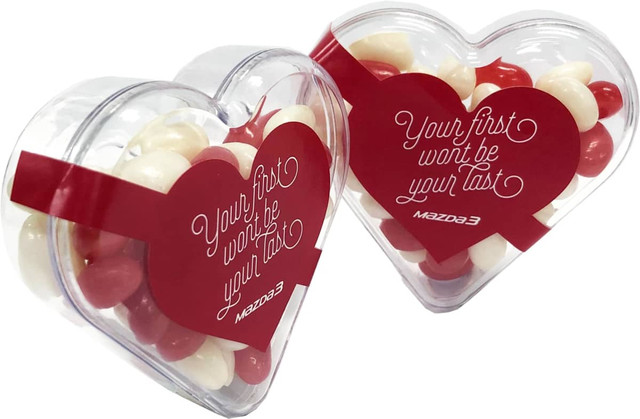 Acrylic heart-shaped container filled with red and white mini jelly beans. It features a logo on the packaging.