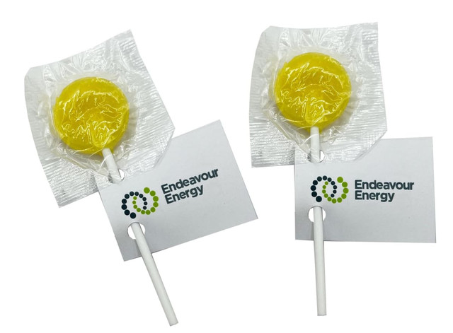 Yellow lollipops wrapped in clear plastic with a white stick and attached tags featuring branding.