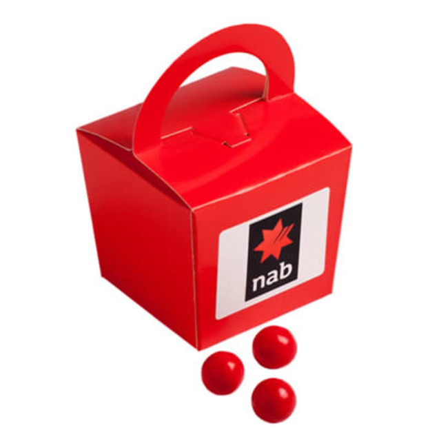 Coloured noodle box in red containing orange choc drops and featuring a logo on the front. Three choc drops are beside it.