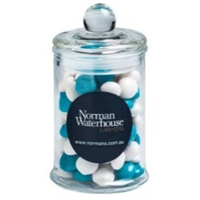 A clear apothecary jar filled with white and blue chewy fruit sweets, topped with a dome lid.