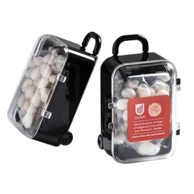 A black carry-on case containing white mints, featuring a transparent lid and a handle. It has a logo on the side.