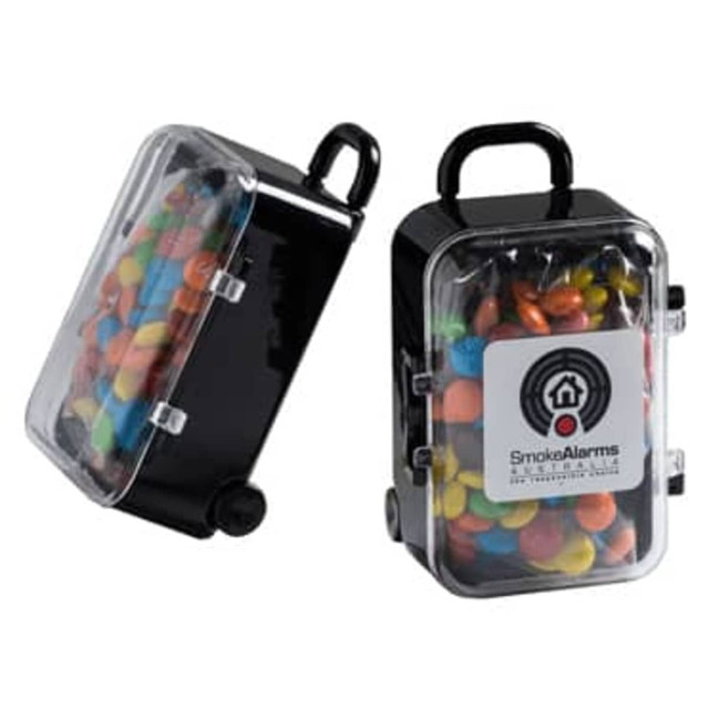 A black carry-on case filled with colourful M&Ms, featuring a transparent lid and a handle.