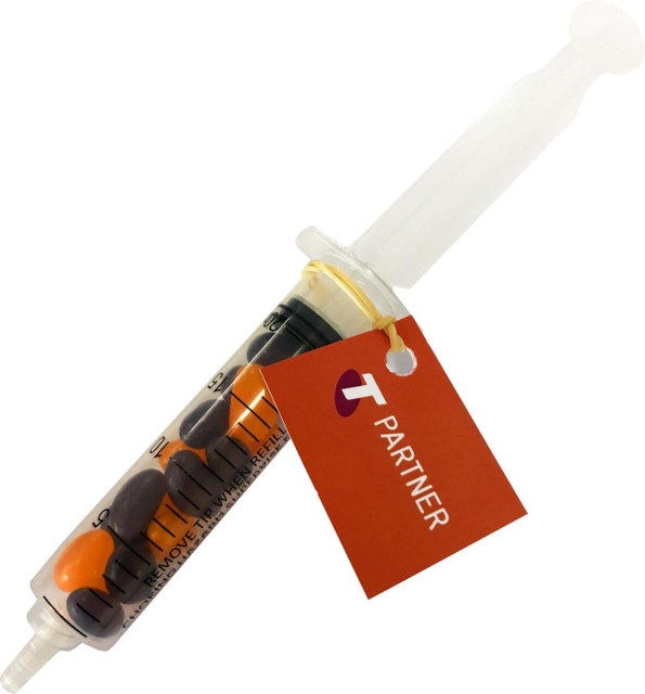A syringe filled with colourful jelly beans, featuring a clear body and a white plunger. It has a tag attached.