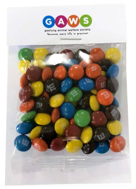 A clear bag filled with colourful M&M chocolates, featuring a mix of red, yellow, blue, green, and brown sweets.