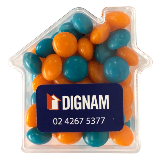 A clear acrylic house-shaped container filled with orange and teal chewy fruit candies. Features a logo.