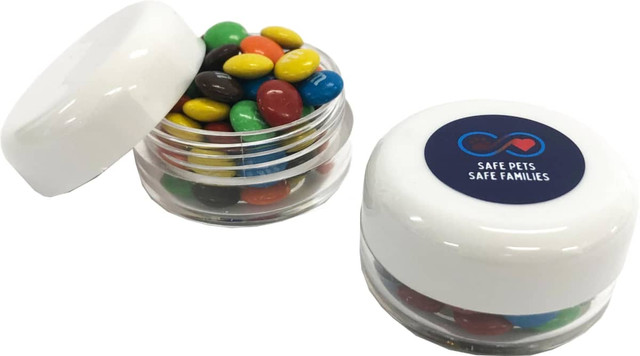 A small screw cap jar with a white lid filled with colourful M&Ms, featuring a logo on the lid.