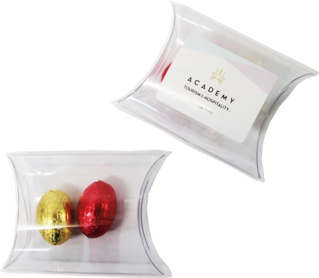 A clear pillow pack containing two mini solid Easter eggs in gold and red. It features a logo on the packaging.