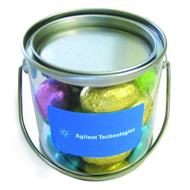 A small bucket containing mini Easter eggs wrapped in vibrant colours, featuring a silver lid and a handle.