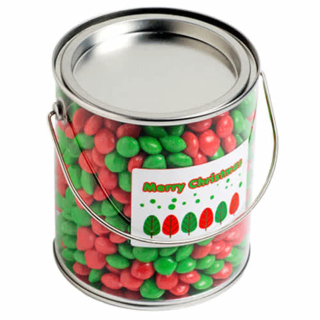 A metal bucket filled with red and green chewy fruit candies. It features a festive label with trees.