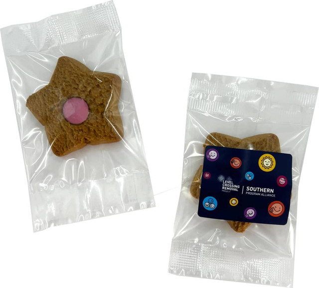 A star-shaped shortbread biscuit in a clear wrapper, featuring a pink centre, accompanied by a branded label.
