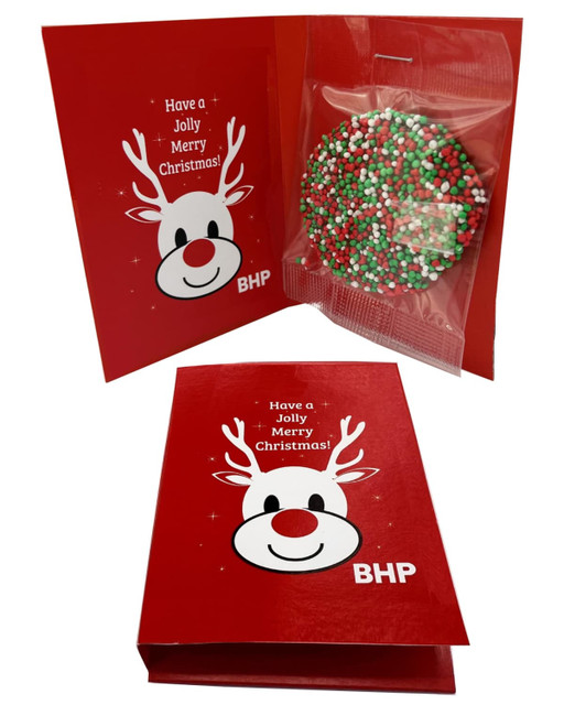 A red gift card featuring a reindeer design, with a chocolate disc decorated in red, green, and white sprinkles inside.
