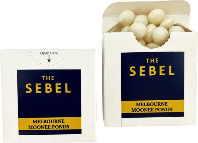 A cardboard box with a flip lid containing white mints, featuring blue and yellow branding.