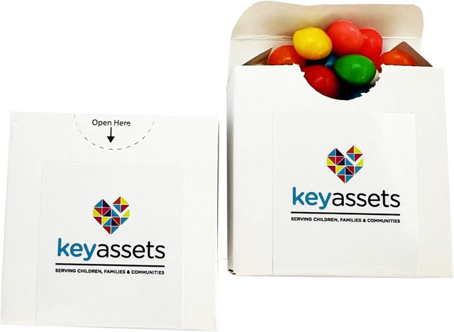 A white flip lid cardboard box containing colourful chewy fruit candies. The box features a logo on the front.