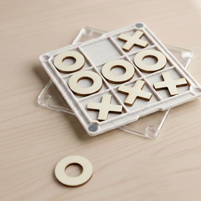 A Tic Tac Toe board game coaster with a clear base, featuring wooden X and O pieces in a grid pattern.