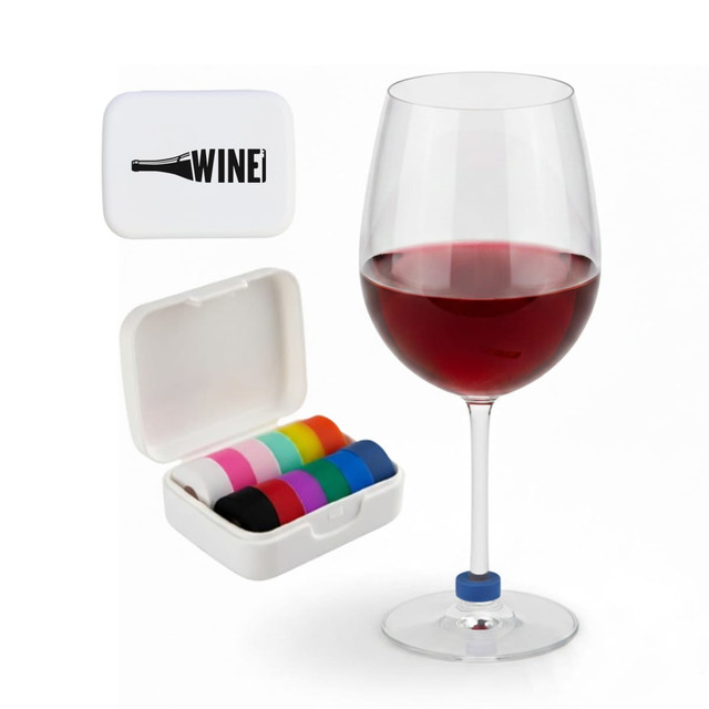 A wine glass filled with red wine beside a white case containing colourful wine glass markers.