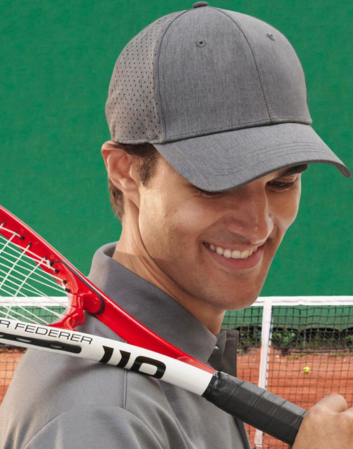 A grey 4-way stretch cap with a perforated design worn by a smiling man holding a tennis racquet.