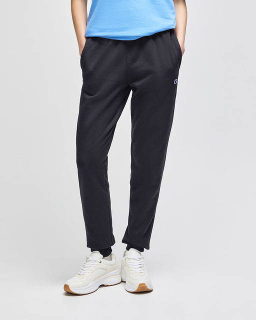 A pair of black fleece jogger pants with side pockets, styled with a light blue top and white shoes.
