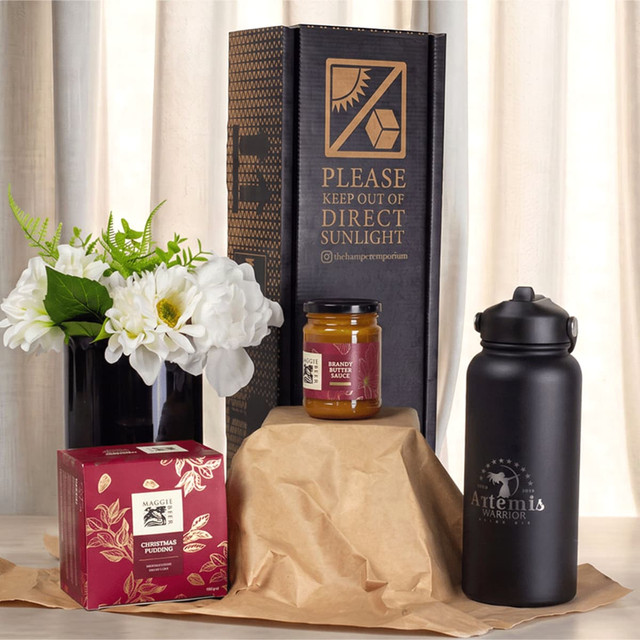 A festive essentials set featuring a black drink bottle, a candle jar, a gift box, and a flower arrangement.