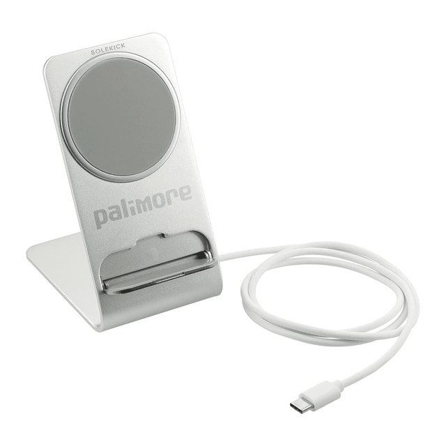 A silver wireless charging stand with a circular charging pad and a white USB-C cable. It features a logo on the base.