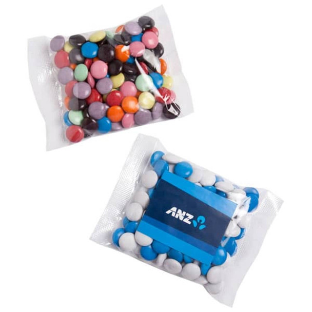 A branded bag containing mixed coloured chocolate beans in various shades, including pastel and dark tones.