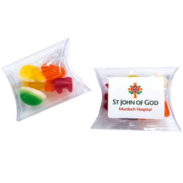 A transparent pillow pack containing assorted mixed lollies in vibrant colours, including red, yellow, green, and orange.