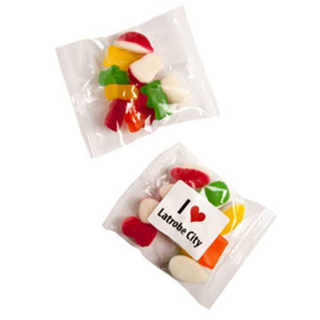A clear bag containing a variety of mixed lollies in bright colours, featuring a branded sticker.