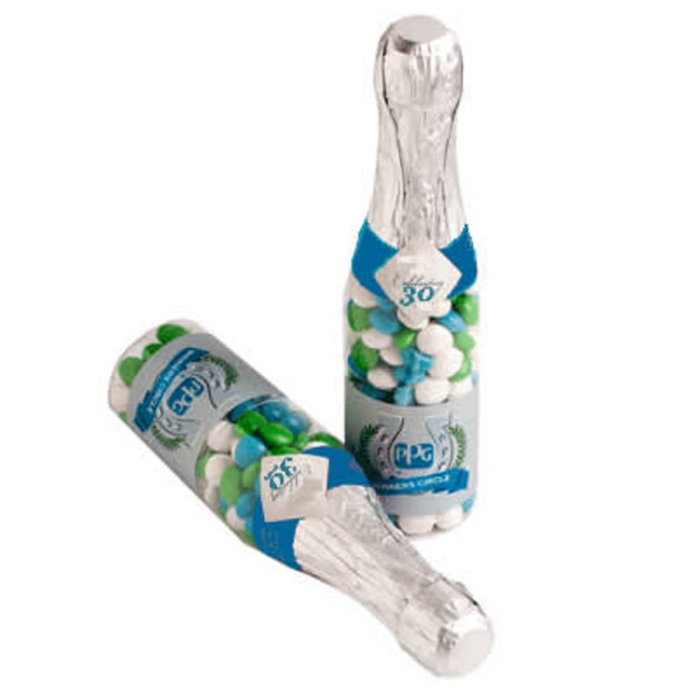 A drink bottle shaped like a champagne bottle, filled with chewy fruits in blue and green, featuring a branding sticker.