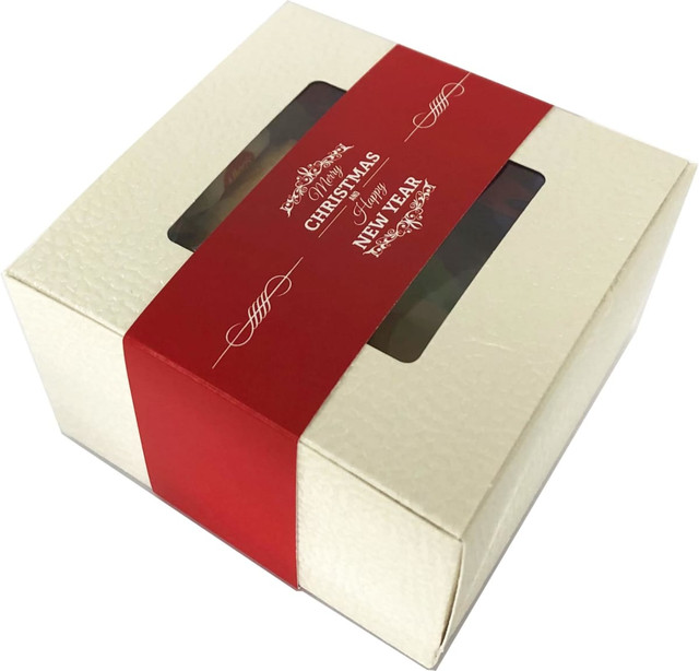 A small cream gift box with a red band contains mixed lollies, featuring a transparent window and a branded logo.