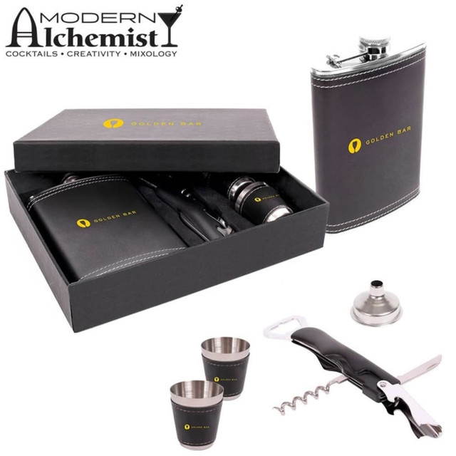 A drink bottle gift set featuring a black flask, two silver cups, a funnel, a corkscrew, and a branded box.