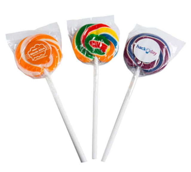 Three colourful candy lollipops in plastic wrapping, featuring orange, green, and purple designs with attached stickers.