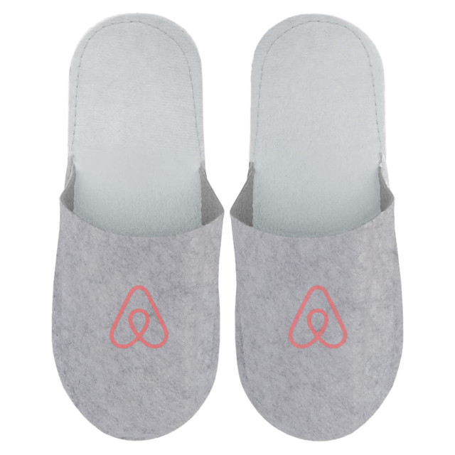 Grey felt slippers featuring a logo on the front, designed for comfort and cosy wear.