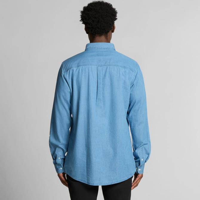 A blue denim button-up shirt with a back pleat and long sleeves, featuring a logo on the collar.