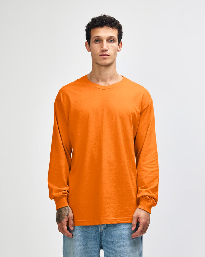 An orange heavyweight cotton unisex long sleeve t-shirt displayed on a model, featuring a logo.