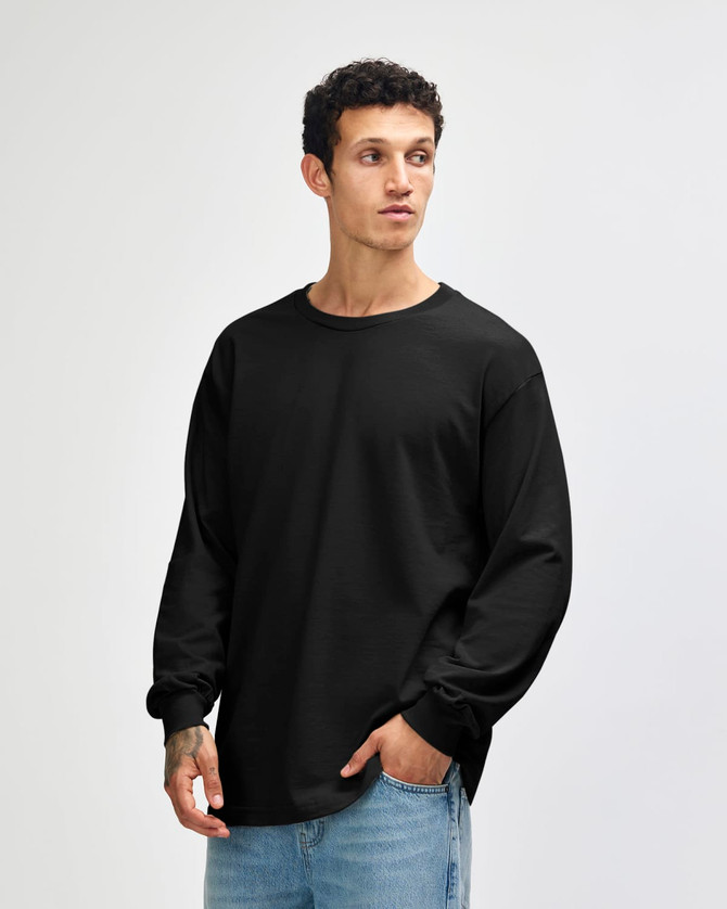 A black heavyweight cotton unisex long sleeve T-shirt worn by a model, featuring a simple design and a logo.