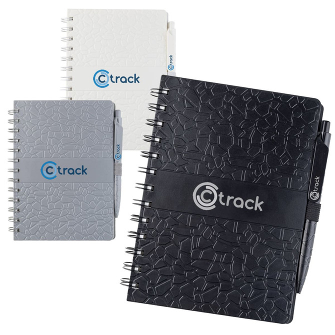 A collection of La Trobe Stone Paper Notebooks in black, grey, and white, featuring a logo and spiral binding.
