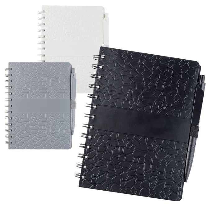 A collection of La Trobe Stone Paper Notebooks in black, grey, and white, featuring an embossed texture and elastic closures.
