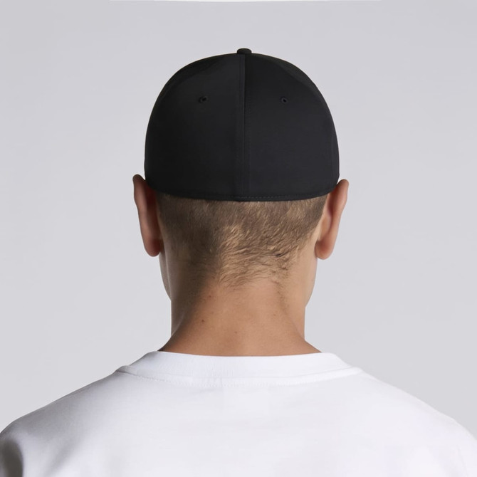 A black cap seen from the back, worn by a person with short hair. The individual is dressed in a white top.