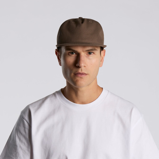 A brown cap with a structured design, featuring a logo, worn by a model in a white t-shirt.