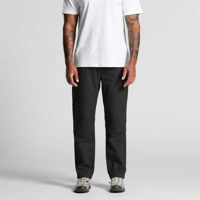 Black cargo pants on a person, paired with a white t-shirt and grey shoes. The pants have a logo.