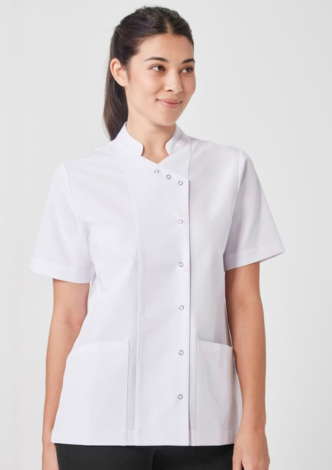 A woman wearing a short-sleeved, white jacket with a mandarin collar and front pockets. The jacket has a logo.