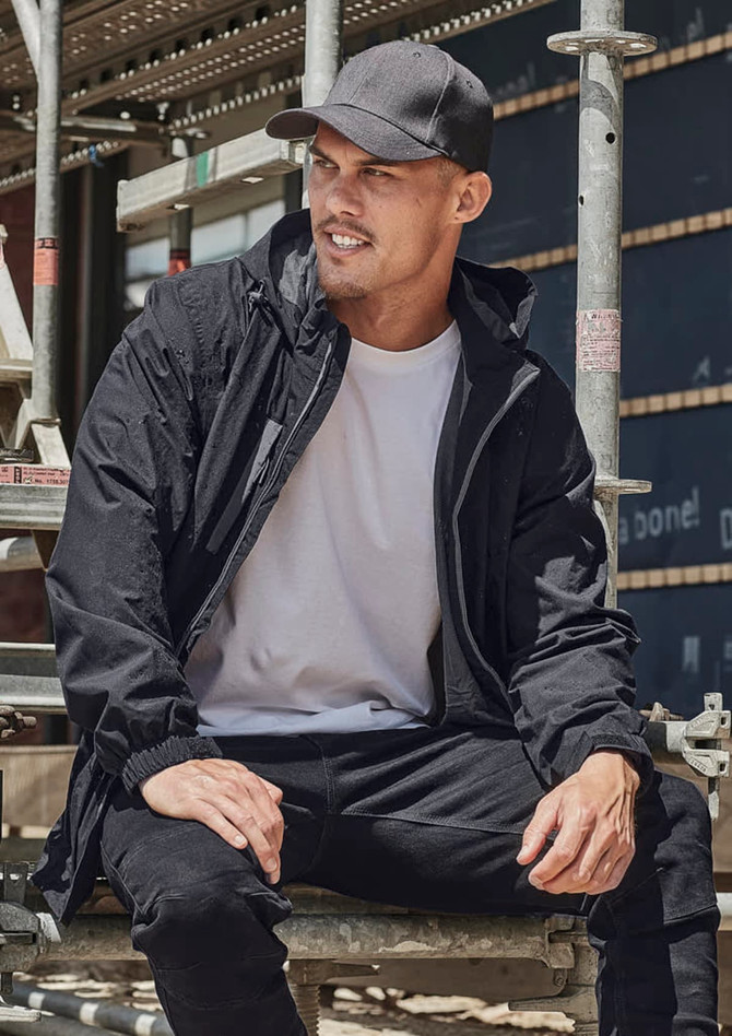 A man wearing a black unisex packable rain jacket sits on scaffolding. The jacket features a hood and has a logo.
