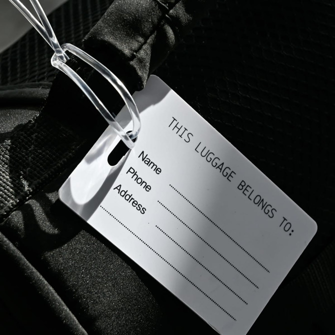A black imprinted mini luggage tag featuring a blank white information card for name, phone, and address.