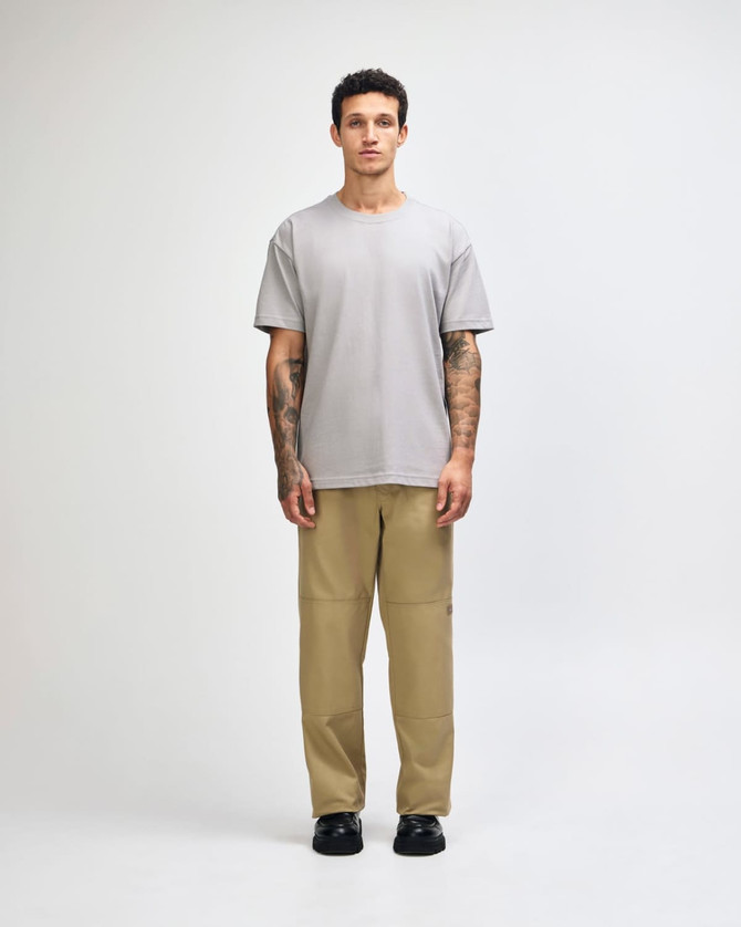 A grey American Apparel Super Heavyweight T-Shirt displayed on a model, paired with light blue jeans and sneakers.