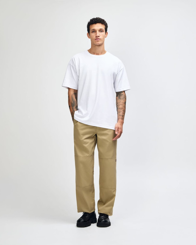 A man wearing a plain white American Apparel Super Heavyweight T-Shirt paired with light blue jeans and black shoes.