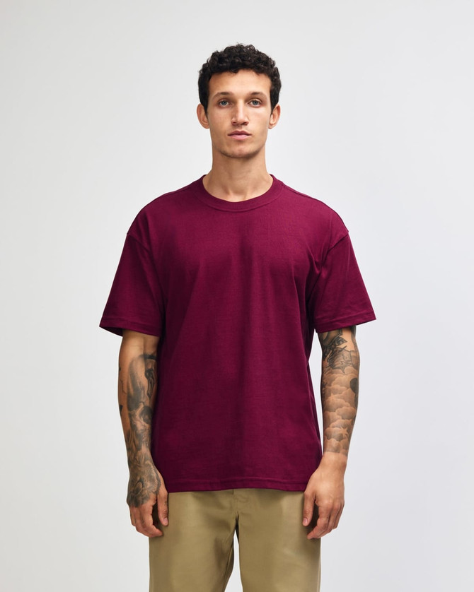 A man is wearing a maroon American Apparel Super Heavyweight T-shirt, standing with a neutral expression.