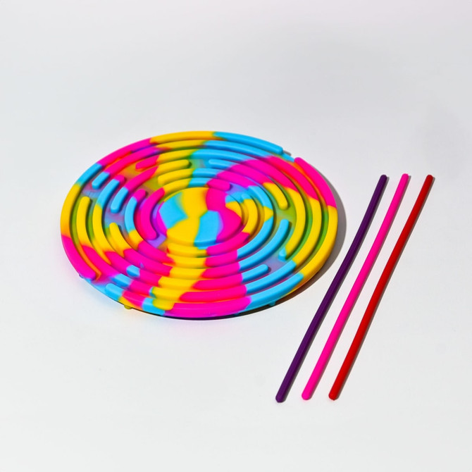 A sensory activity board in rainbow colours, featuring a swirl design and three coloured straws beside it.
