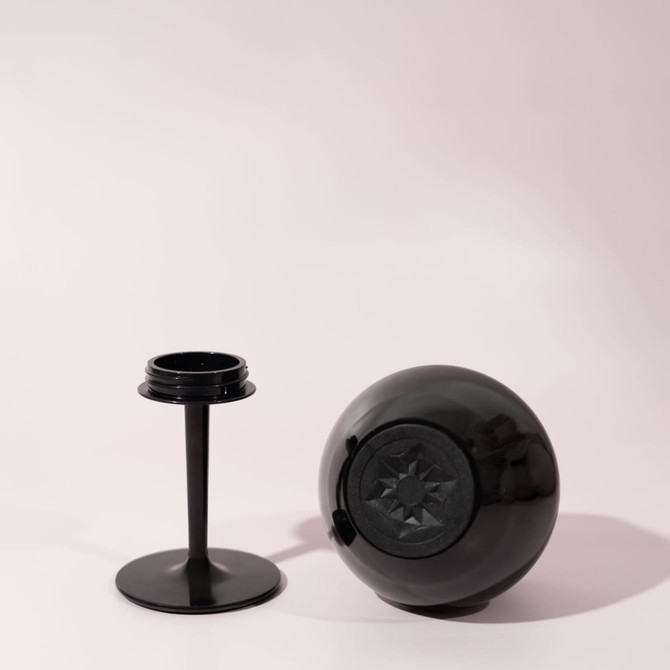 A black detachable wine glass with a round base and a separate stem, set against a light background.