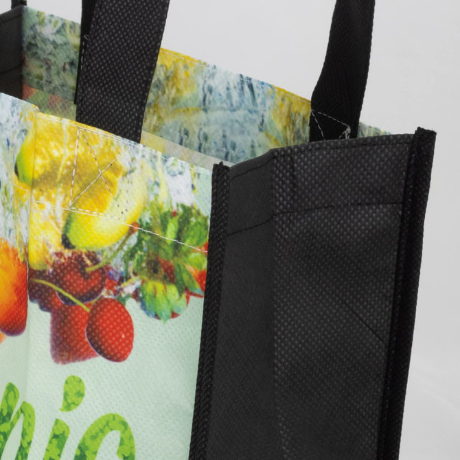 A black tote bag with a colourful graphic design featuring fruits and vegetables. The bag has sturdy handles.